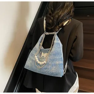 Detail of blue denim backpack with butterfly metal patches and pearl chain accents