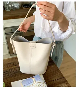 Détail d'un sac seau blanc crème avec texture lychee et boucle magnétique élégante