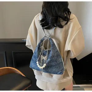 Detail of blue glitter denim tote bag featuring silver chains and white pearl charms