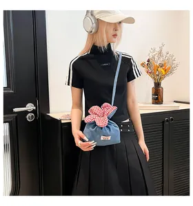 Detailaufnahme der hellblauen Denim-Umhängetasche mit rot karierter Blumen-Kordelzugverzierung