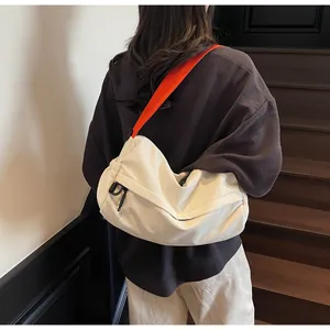 Detail of white nylon messenger bag with contrasting orange strap on wood stairs