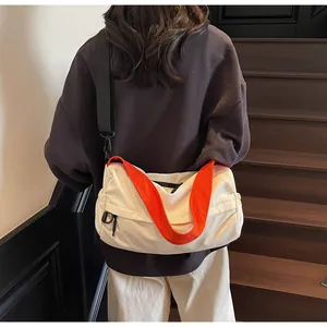Detail view of large capacity crossbody bag with orange handle and adjustable strap