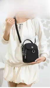 Detail of black nylon multi-pocket crossbody bag with metallic logo and adjustable strap