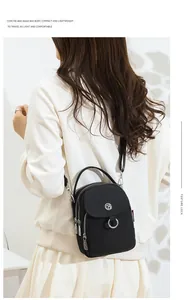 Detail of black multi-zip crossbody bag with silver hardware and top handle strap