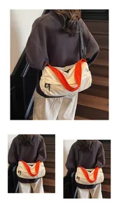 Detail of a cream bucket bag with contrasting orange handles and adjustable black strap