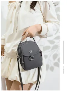 Detail of grey crossbody bag with metallic logo and textured waterproof fabric material