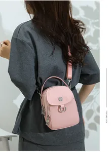Detail view of the pink crossbody bag on a model showing metal logo and texture lock