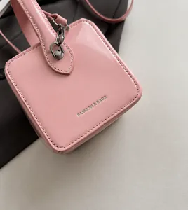 Detail of pink glossy patent leather box bag with silver FASHION & BAGS lettering