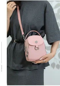 Detail of light pink nylon crossbody bag showing multiple silver zippers and textured flap