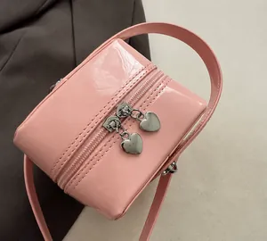 Detail of pink patent leather box bag featuring silver heart-shaped zipper pulls