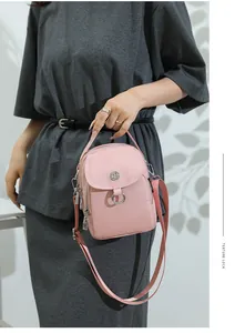 Detail of pink mini crossbody bag with silver hardware held by model in natural light