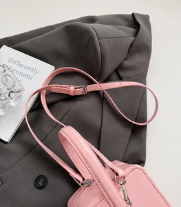 Detail of adjustable pink leather strap and polished metal buckle on fashion box bag