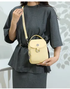 Detail showing the light yellow fabric crossbody bag with adjustable strap and leaf shadow