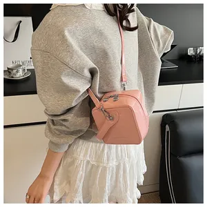 Detail of pink patent leather box bag with silver hardware and adjustable strap