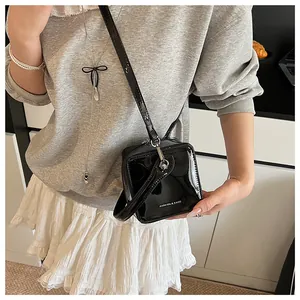 Mini black patent leather box bag shown worn on shoulder by a model for size scale