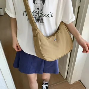 Modèle portant un sac bandoulière kaki en forme de demi-lune avec large sangle