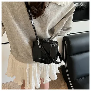 Rear view of black patent leather box bag with silver hardware on a model outfit