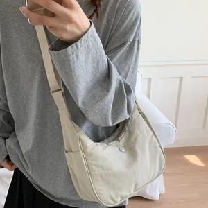 Détail du sac baguette en nylon crème avec bandoulière large et logo métallique