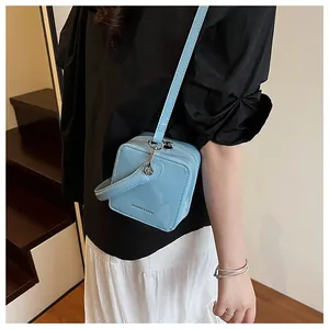 Detail of light blue patent leather crossbody box bag shown on a model