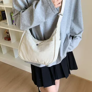 Détail du sac à bandoulière beige minimaliste en forme de croissant avec sangle réglable