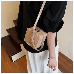 Detail of a beige patent leather square box bag with glossy finish and silver zippers