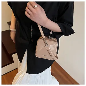 Detail of apricot patent leather mini box bag with Fashion & Bags text and metal strap clips