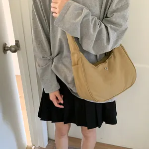 Sac croissant kaki avec logo argenté porté par un mannequin en tenue décontractée