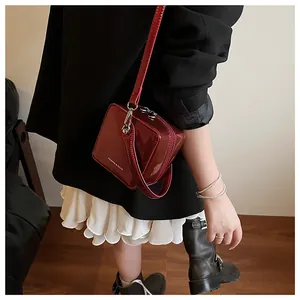 Model wearing dark red patent leather square crossbody bag with white fashion text print