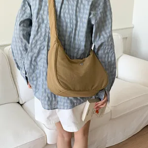 Détail d'un sac hobo croissant kaki avec logo métallique sur tissu en nylon texturé