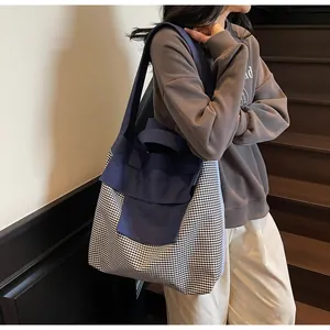 Dettaglio della grande borsa tote in tela con motivo vichy bianco e nero e tracolla blu