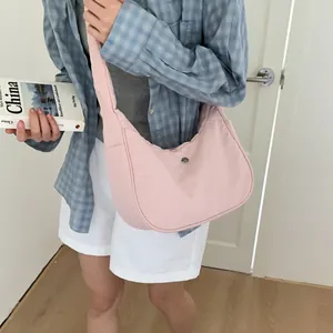 Détail du sac demi-lune rose montrant la texture mate et le bouton logo en métal rond