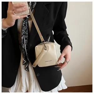 Close-up of cream square crossbody box bag with glossy finish and fashion text detail
