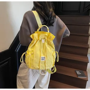 Side view of a bright yellow drawstring backpack with crinkled fabric and adjustable straps