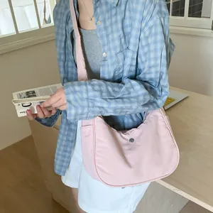 Détail d'un sac demi-lune en nylon rose clair avec large bandoulière en situation
