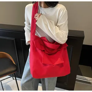 Dettaglio di una borsa tote grande in tela rossa con un grande fiocco e tracolla larga