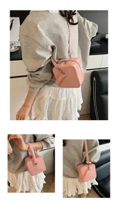 Detail of pink mini box bag with top handle, crossbody strap, and polished finish