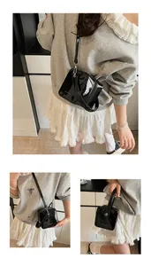 Three-way view of glossy black patent leather box bag with dual zippers and strap