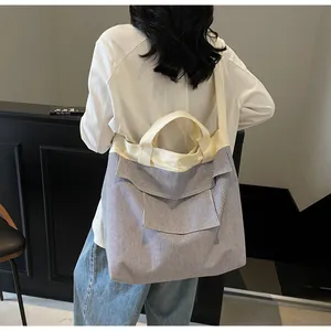 Dettaglio della borsa tote in tela a righe blu e bianche con spalline crema e tasca frontale