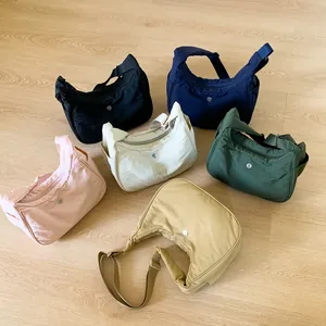 Sacs à bandoulière demi-lune en nylon en six couleurs vives sur un sol en bois clair
