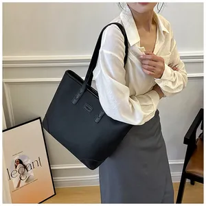 Detail of black pebbled leather tote bag showing large capacity and elegant shoulder straps