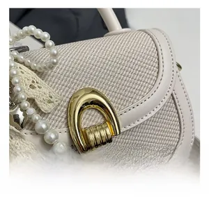 Détail du fermoir en U doré avec pendentif perle et texture tweed sur un sac beige