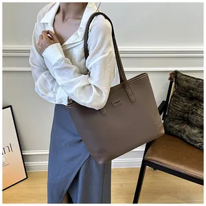 Deep brown pebble leather tote bag shown on shoulder in a minimalist indoor setting