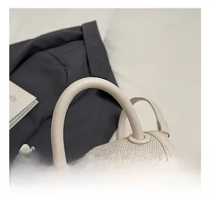 Détail du sac selle tissé beige avec chaîne de perles et finitions en dentelle