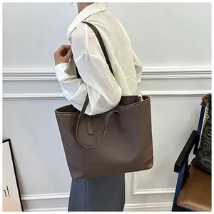Detail view of a large brown leather tote bag with reinforced corners and shoulder straps