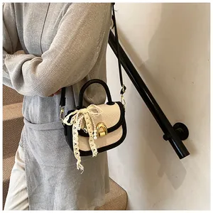 Détail d'un sac selle tissé chic avec bordure en cuir noir et nœud en dentelle perlé