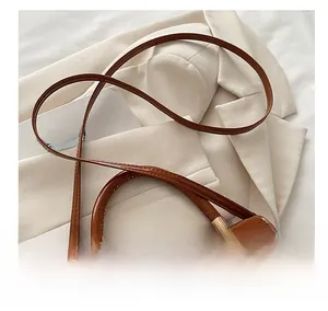 Détail du sac en cuir verni marron avec poignée ronde et éléments en métal doré