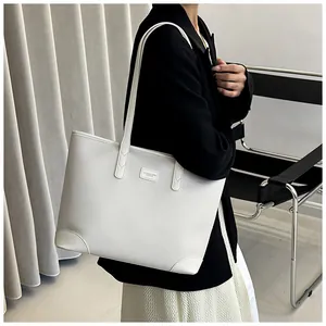 Detailed close-up of white pebble leather tote bag with logo plaque and sturdy shoulder straps