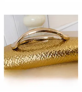 Close-up of golden square handbag showing textured snakeskin pattern and metal handle