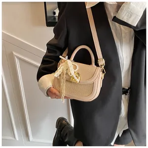 Détail du sac selle beige avec nœud en dentelle de perles et boucle dorée ronde