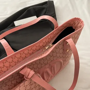 Detailed close-up of smooth metal zipper and pink leather handle on a printed tote bag